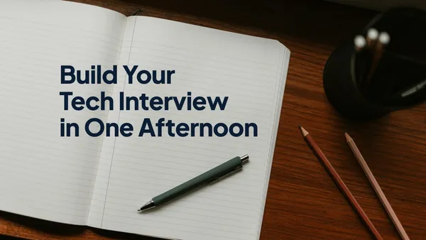 An open lined notebook with a pen on a wooden desk, with the headline "Build Your Tech Interview in One Afternoon" on the page