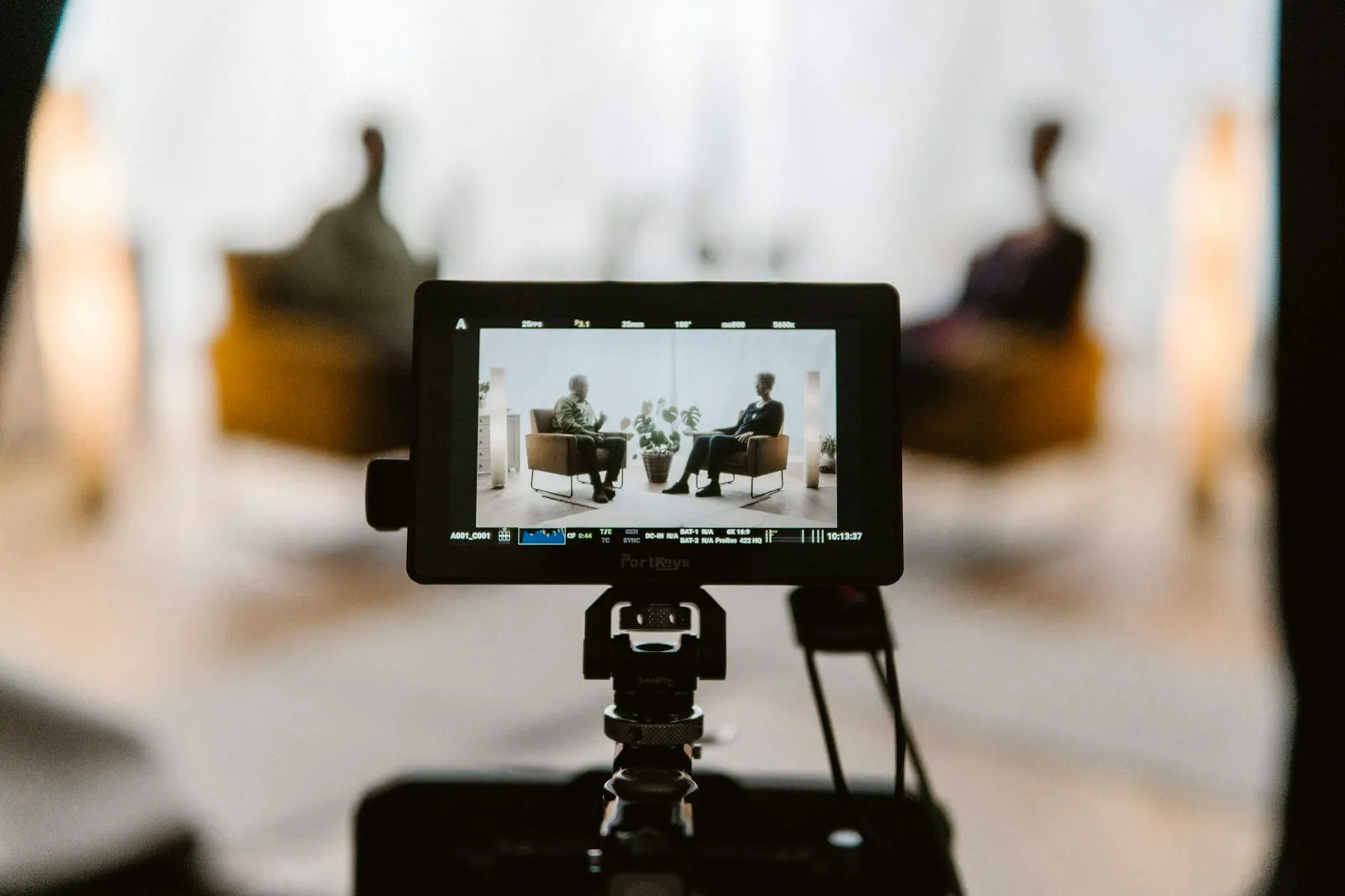 A camera monitor on a tripod showing a recorded interview in progress