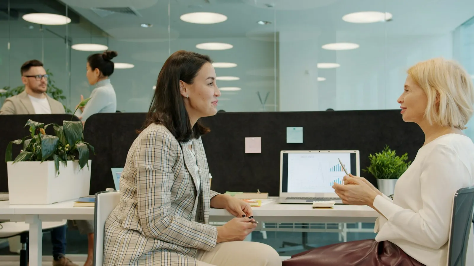 Two colleagues talking casually at a desk in an office