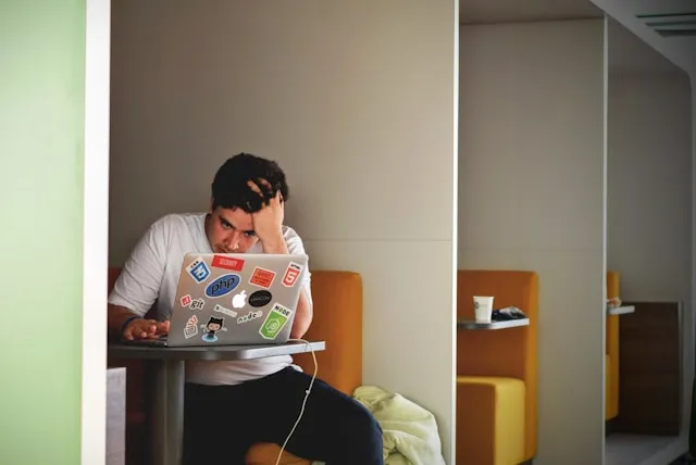A stressed developer with his hand on his head in front of a laptop